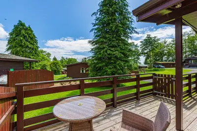a patio with a table and chairs on a fence at Bluebell Lodge 11 with Hot Tub in Newton Stewart