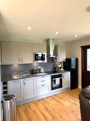 a kitchen with white cabinets and a black refrigerator at Bluebell Lodge 11 with Hot Tub in Newton Stewart