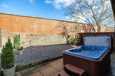 a hot tub in a yard next to a brick wall at Bluebell Lodge 24 with Hot Tub in Newton Stewart
