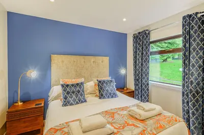 a bedroom with a large bed with a blue wall at Birch Lodge 13 with Hot Tub in Newton Stewart