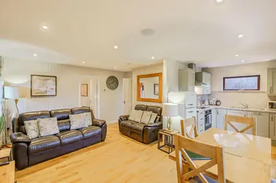 a living room with two leather couches and a kitchen at Birch Lodge 13 with Hot Tub in Newton Stewart