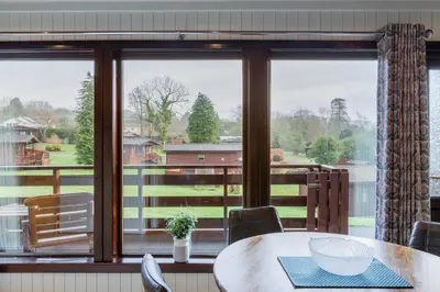 a dining room with a table and a large window at Birch Lodge 14 with Hot Tub in Newton Stewart