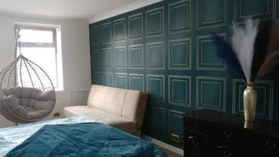 a bedroom with a green wall with a chair and a bed at Dunoon Gourock Inverkip Apartment in Gourock