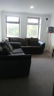 a living room with two black couches and two windows at Dunoon Gourock Inverkip Apartment in Gourock