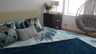 a bed with pillows and a chair in a bedroom at Dunoon Gourock Inverkip Apartment in Gourock