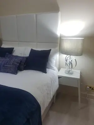 a bedroom with a bed and a lamp on a table at Dunoon Gourock Inverkip Apartment in Gourock