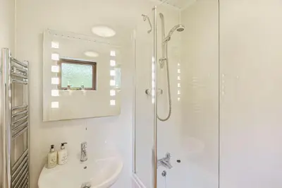 a white bathroom with a shower and a sink at Birch Lodge 19 with Hot Tub in Newton Stewart