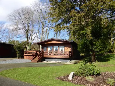 a small cabin with a porch in a yard at Birch Lodge 22 with Hot Tub in Newton Stewart