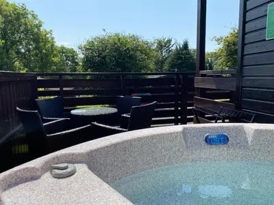 a hot tub on a patio with chairs and a table at Conifer Lodge 8 with Hot Tub in Newton Stewart