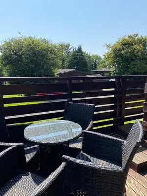 a patio with a table and chairs on a deck at Conifer Lodge 8 with Hot Tub in Newton Stewart