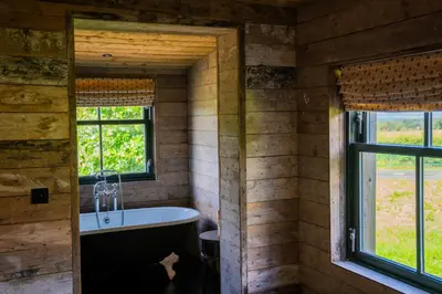 a bathroom with a tub and two windows at The Artist's House at Jupiter Artland in Kirknewton