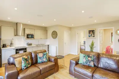 a living room with two leather couches and a kitchen at Conifer Lodge 25 with Hot Tub in Newton Stewart