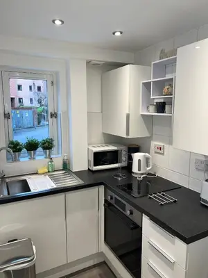a kitchen with white cabinets and a black counter top at Merchantcityflat in Glasgow