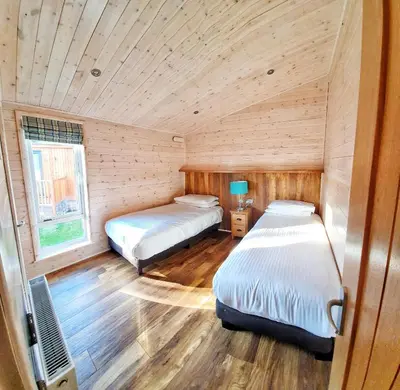 two beds in a room with wooden walls at Skyline Lodge Loch Lomond Castle Lodges in Balloch