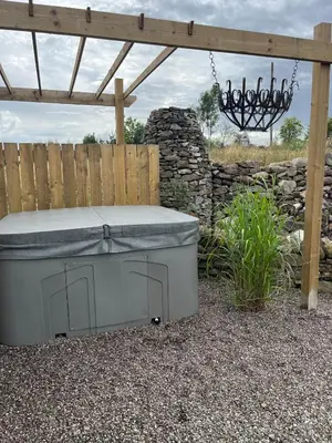 a hot tub sitting under a pergola in a yard at The Bothy in Stirling