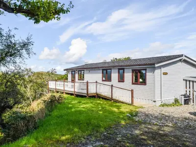 a small white house with a large deck at Catkin Lodge - Uk39646 in Lunga