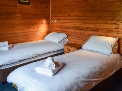 two beds in a room with wooden walls at Catkin Lodge - Uk39646 in Lunga
