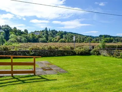 a wooden bench sitting in a field of grass at Birch - Apartment in Aberfoyle