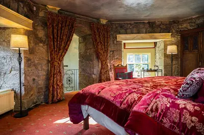 a bedroom with a large bed in a stone wall at Craigiehall Temple in Edinburgh