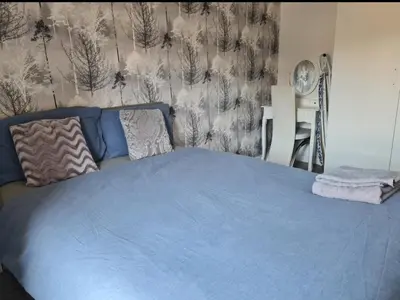 a bedroom with a blue bed with a blue blanket at City, Celtic park & Emirates Stadium Apartment, for families or age over 23 in Glasgow