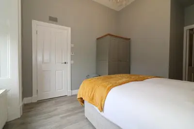 a bedroom with a white bed with an orange blanket at Signature - Linden House Flat 3 in Airdrie