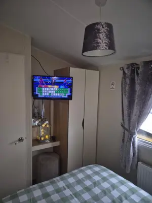 a bedroom with a bed and a flat screen tv at 3 bedroom Caravan Craigtara in Ayr