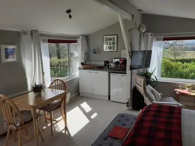 a living room with a table and a kitchen at The Old School Bike Shed in Stirling