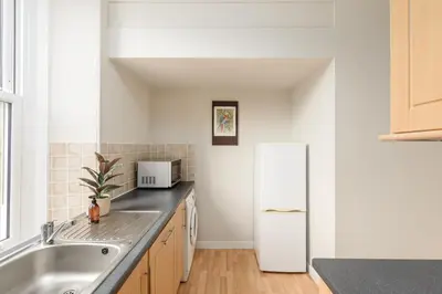 a kitchen with a sink and a refrigerator at The Stockbridge Snug by Calton Living in Edinburgh