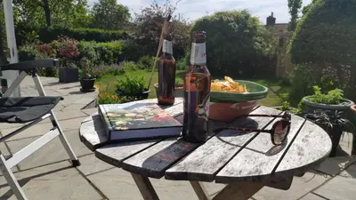 a bottle of beer and a book on a wooden table at Chilowen - Happy House in Inverkeithing