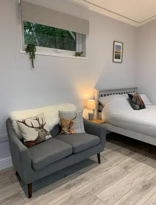 a living room with a couch and a bed at Lora Cabin in Oban