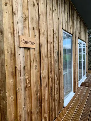 a wooden wall with a sign on the side of a house at Lora Cabin in Oban