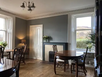a dining room with a table and a fireplace at Blarcreen in Oban