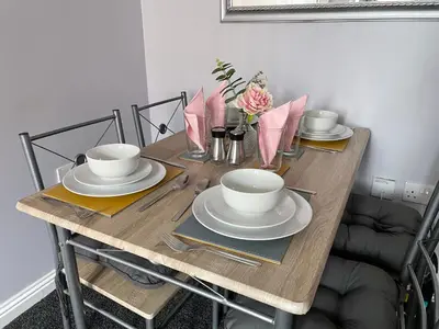 a wooden table with plates and bowls on it at Spacious one bedroom flat, entire property. in Greenock