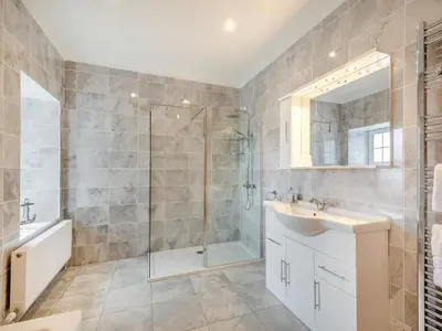 a bathroom with a shower and a sink and a mirror at Kerrytonlia Cottage in Mountstuart