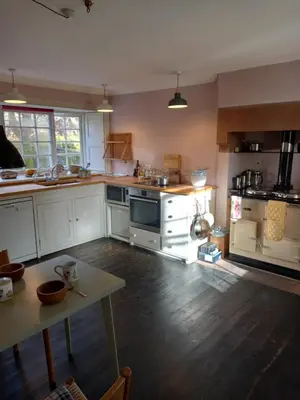 a kitchen with white cabinets and a wooden floor at Riverside House in Thornhill
