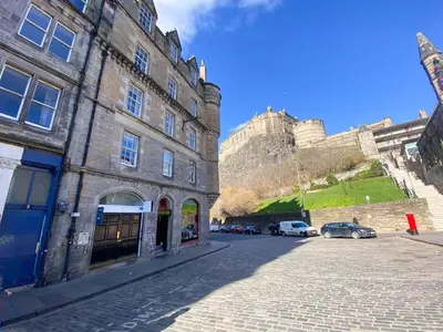 a street in front of a building with a castle in the background at Snug Studio on The Grassmarket, 5mins from Castle in Edinburgh