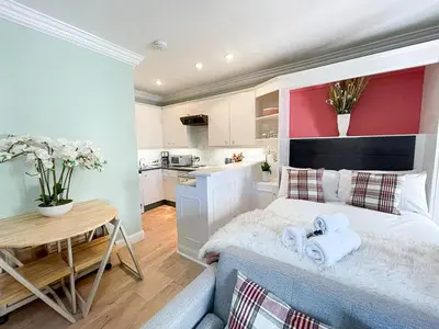 a bedroom with a bed and a table and a kitchen at Snug Studio on The Grassmarket, 5mins from Castle in Edinburgh