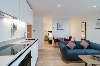 a living room with a blue couch and a table at PREMIER SUITES Edinburgh Fountain Court in Edinburgh