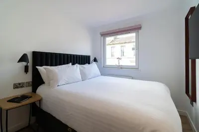 a bedroom with a large white bed with a window at PREMIER SUITES Edinburgh Fountain Court in Edinburgh
