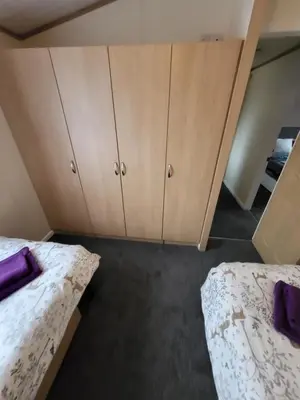 two beds in a room with cabinets and purple pillows at Red Squirrel Lodge in Auchterarder