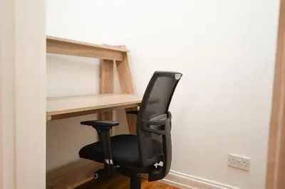 a black chair sitting in front of a computer desk at Glasgow - 2 Bedroom Apartment in Glasgow