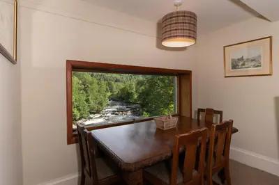 a dining room with a table and a window at Gatehouse, Bridge of Balgie, Glenlyon in Bridge of Balgie