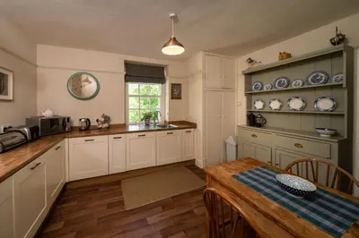 a kitchen with white cabinets and a wooden table at Gatehouse, Bridge of Balgie, Glenlyon in Bridge of Balgie