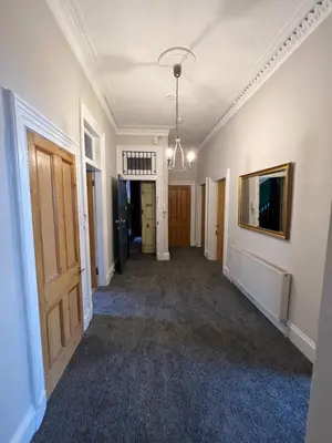 an empty hallway in a house with a door and a painting at Sauchiehall Street West End Apartment in Glasgow