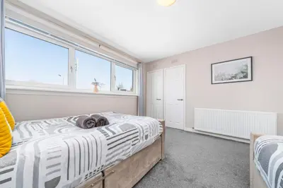 a bedroom with a bed and a large window at Quirky, Family Home in Glasgow in Cardonald