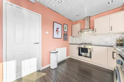 a kitchen with orange walls and a white door at Quirky, Family Home in Glasgow in Cardonald