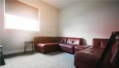 a living room with a brown leather couch and a window at Garnock House in Beith