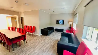 a living room with a table and red chairs at Garnock House in Beith