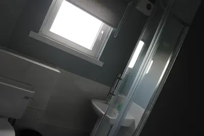 a bathroom with a shower and a sink and a window at Garnock House in Beith