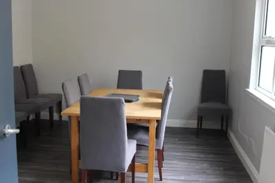 a dining room table with chairs and a laptop on it at Garnock House in Beith